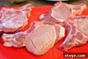 Pork chops being scored to prevent curling during cooking