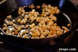 Hearty White Bean and Cabbage Stew 10 Closer view of the potatoes browning in the skillet, with some edges turning golden.
