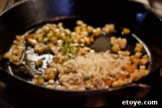 Hearty White Bean and Cabbage Stew 11 Fresh thyme sprigs being added to the browning potatoes in the skillet.
