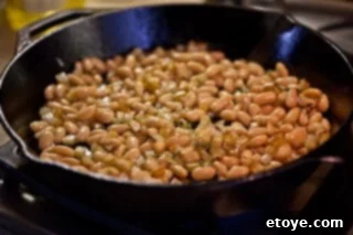 Hearty White Bean and Cabbage Stew 12 White beans, thyme, and onion added to the skillet with potatoes, beginning to cook and brown.