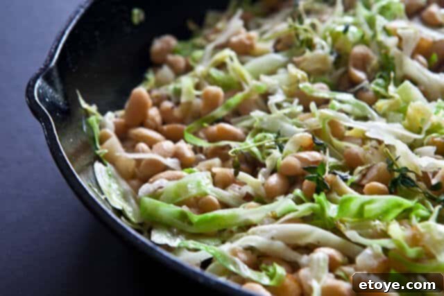 Hearty White Bean and Cabbage Stew 4 Another perspective of the cooked white beans, cabbage, and potatoes, showing steam rising from the skillet.