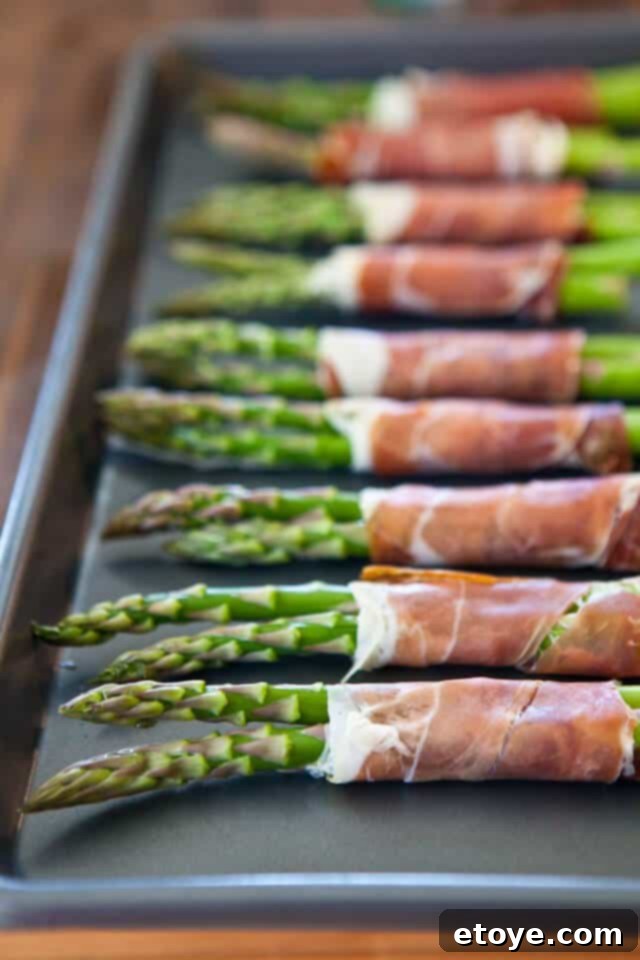 Drizzling olive oil on asparagus tips, avoiding prosciutto