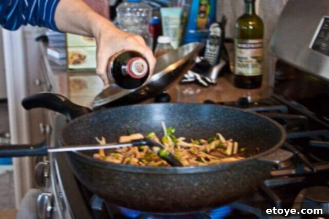 Savory Nian Gao Stir-Fry 13 Drained sticky rice cakes being added to the stir-fry in the wok.