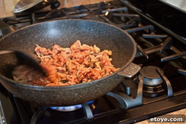 Savory Nian Gao Stir-Fry 7 Thinly sliced marinated pork being stir-fried in a hot wok until almost cooked through.