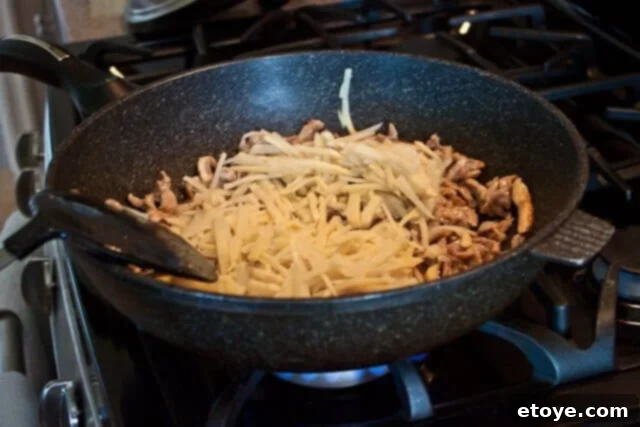 Savory Nian Gao Stir-Fry 10 Shredded Napa cabbage added to the wok, ready to be stir-fried with other ingredients.