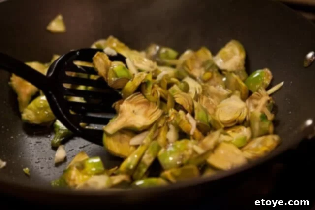 Sautéed artichokes and garlic being tossed in a pan.