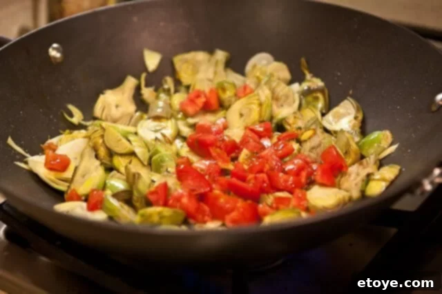 Chopped fresh tomatoes added to the artichoke and garlic mixture.