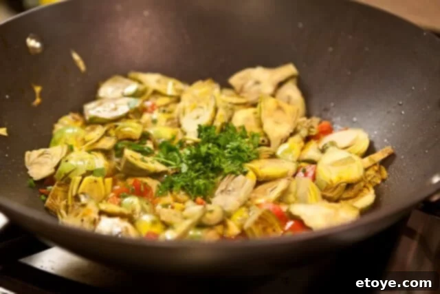 Adding fresh parsley to the cooked baby artichokes.