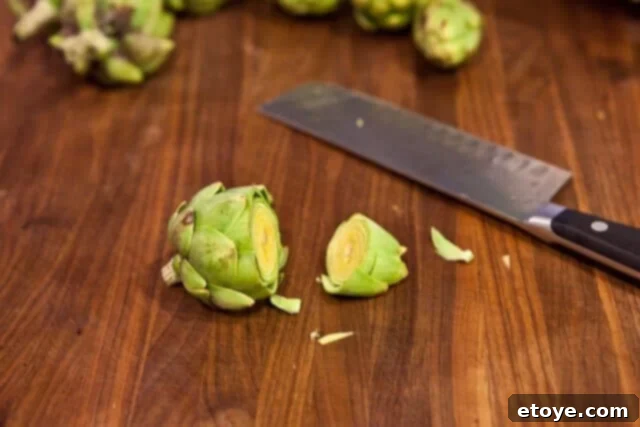Cutting the top portion of a baby artichoke.