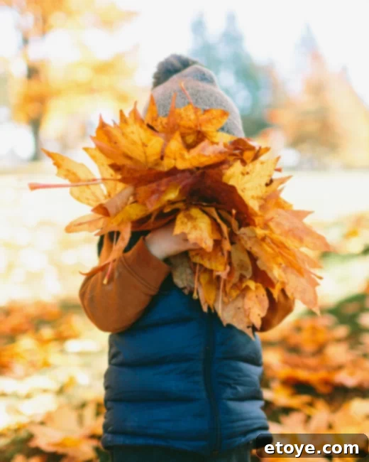 Child happily hugging autumn leaves - Celebrating the joyful spirit of fall
