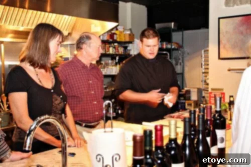 Carrie, Jeffrey, and Chef Eddie with many wine bottles