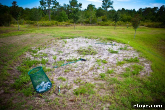 A sand trap on a golf course with scattered debris in a trash can, hinting at past use