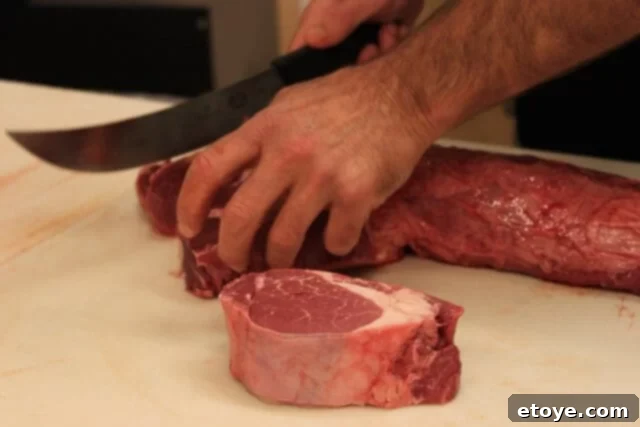 Butcher demonstrating how to trim fat and silver skin from a sliced filet mignon