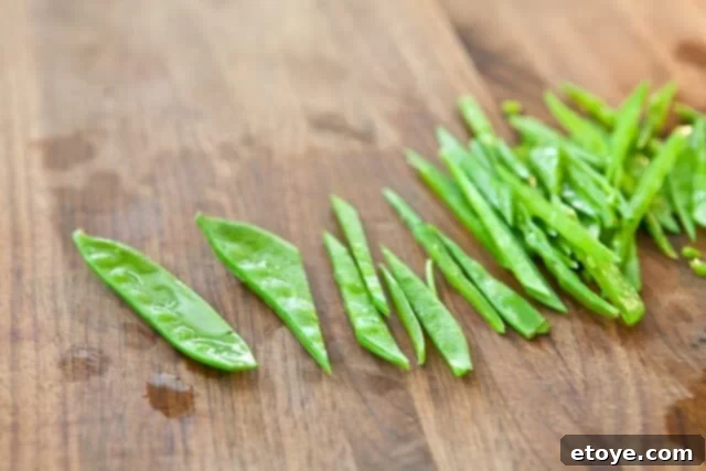 Citrus Ponzu Cabbage Crunch 3 Detailed shot of snow peas being sliced diagonally into thin matchsticks