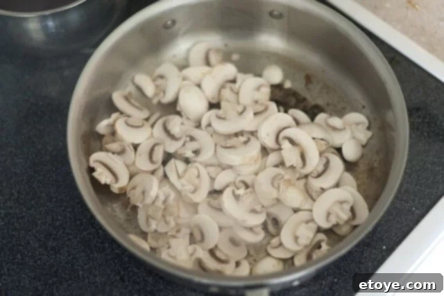 cooking steak_6 Sautéing sliced button mushrooms in a pan.