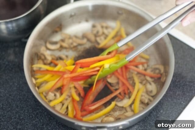 cooking steak_7 Adding bell peppers to the sautéing mushrooms in a pan.