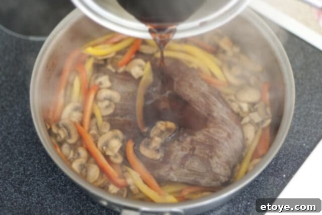 cooking steak_9 Pouring homemade teriyaki sauce over seared steak, mushrooms, and peppers in a pan.