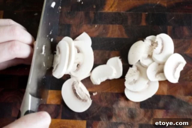 preparing steak_2 Slicing button mushrooms on a cutting board.