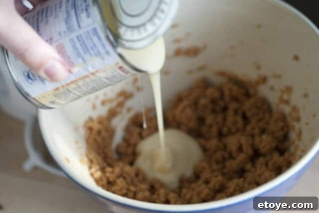 Peanut Butter Pie Powdered Sugar Confectioner's sugar is being slowly added to the peanut butter filling mixture with a mixer.