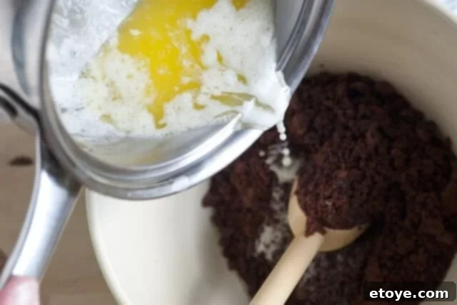 Peanut Butter Pie Crust Press Chocolate cookie crumbs are poured into a pie dish, ready to be pressed into the crust.