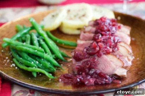 Seared Duck Breast with Sweet and Sour Cranberry Chutney: A Gourmet Meal A close-up view of the perfectly seared duck breast, glistening with its crispy skin, served alongside a vibrant dollop of sweet and sour cranberry chutney, ready to be enjoyed.