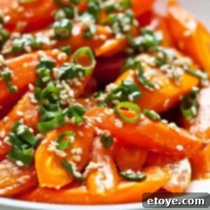 Plated Roasted Carrots with Sesame Ponzu Vinaigrette garnished with green onions and sesame seeds.