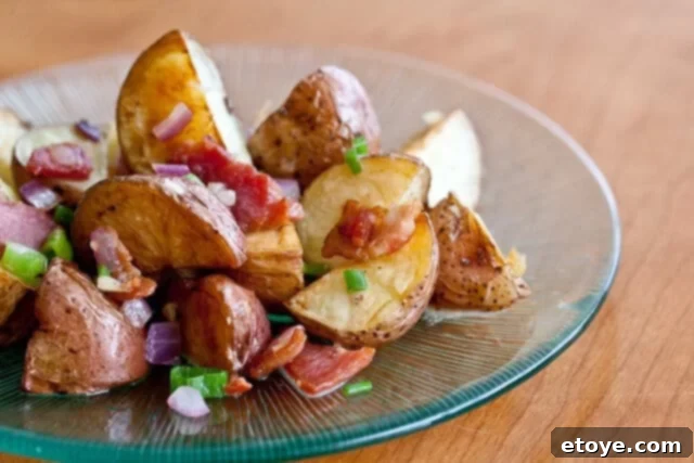 Warm Bacon Potato Salad served elegantly on a glass plate, showcasing crispy bacon and golden roasted potatoes.