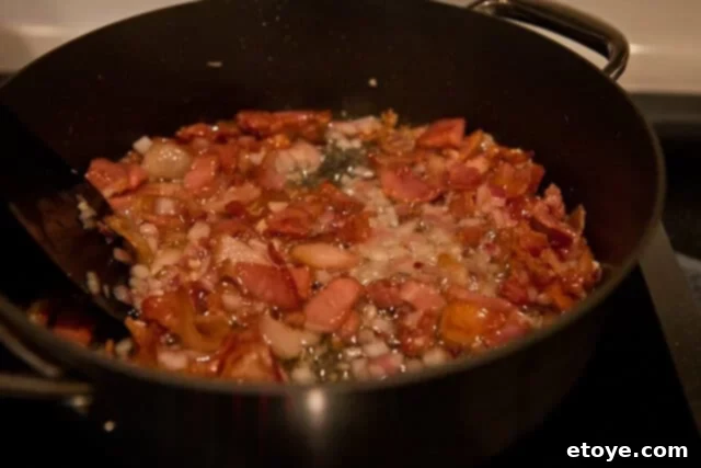 Perfectly cooked crispy bacon, garlic, and onions in a skillet, ready to be incorporated into the warm potato salad.