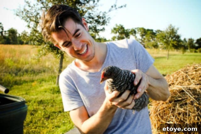 John Gregory Smith cautiously holding a large chicken, looking amused