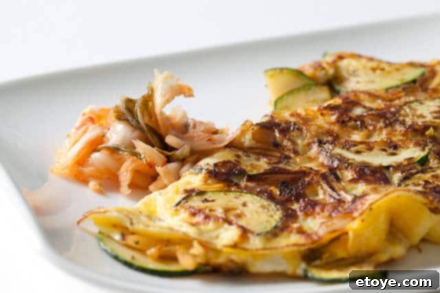 Delicious and vibrant kimchi omelet served on a white plate, ready to eat