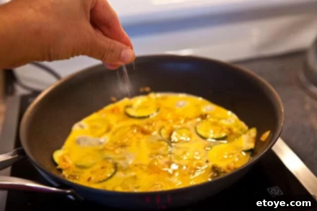 Seasoning a kimchi omelet cooking in a pan with salt and pepper
