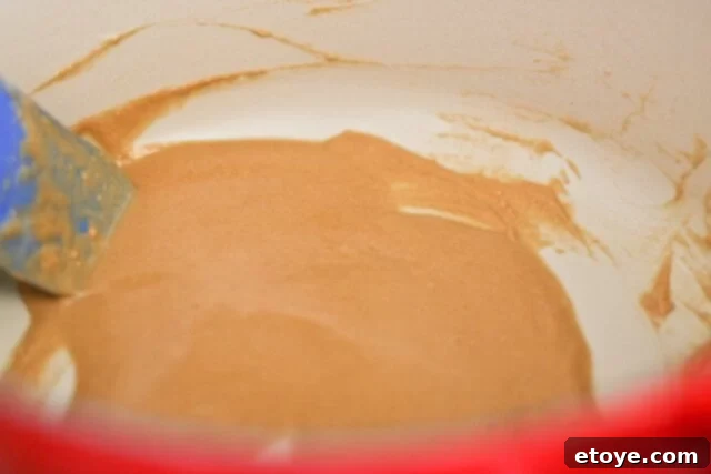 Chopped onions, celery, and green bell peppers, the 'holy trinity', with sliced smoked sausage and other vegetables on a cutting board.