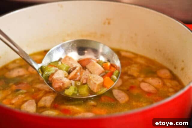 Fresh or frozen okra being added to the simmering gumbo, an essential ingredient for flavor and texture.