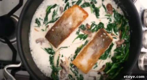 Pan-Seared Salmon with Creamy Spinach and Mushroom Sauce 5 Four pan-seared salmon fillets simmering in a rich creamy mushroom and spinach sauce, ready to be served.