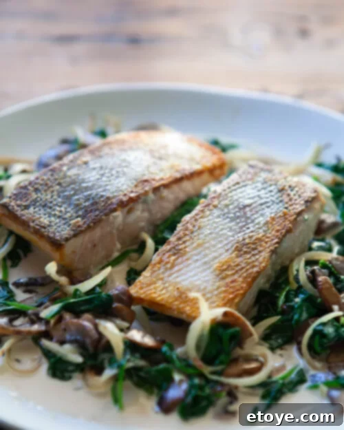 Pan-Seared Salmon with Creamy Spinach and Mushroom Sauce 9 A beautifully plated portion of salmon with creamy spinach and mushroom sauce, garnished with fresh herbs, showcasing its rich texture.