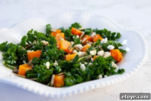 Vibrant roasted butternut squash and kale salad with crumbled feta, generously drizzled with a homemade walnut vinaigrette, perfect for combating winter blues and boosting mood.