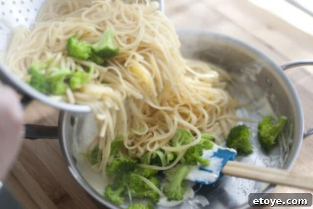 Rich Miso Chicken Pasta 9 Shredded Parmigiano-Reggiano cheese being sprinkled over the pasta and sauce in the skillet.