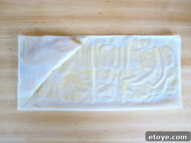 Maintaining Triangle Shape Continuing the flag-like fold of the filo dough to maintain the triangle shape