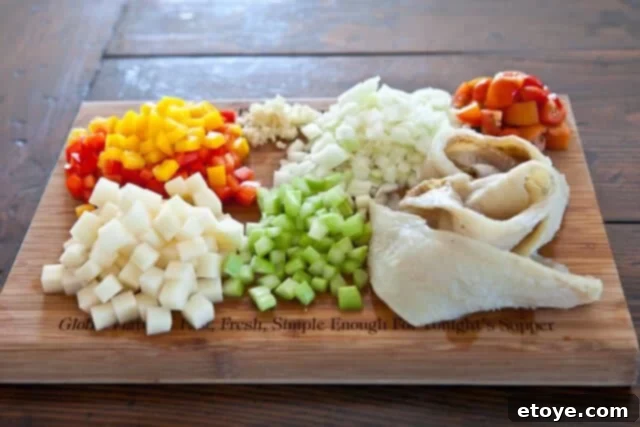 Assortment of fresh ingredients for Bacalao recipe, including diced bell pepper, garlic, onion, tomatoes, celery, and potatoes alongside desalinated salt cod