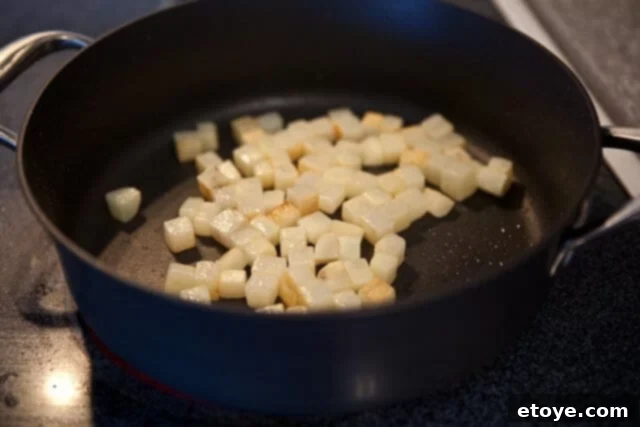 Diced potatoes browning in a hot sauté pan with olive oil