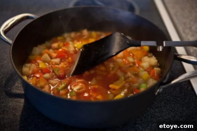 Freshly diced vegetables and tomato paste simmering in a pot, ready for the salt cod to be added