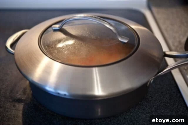 Covered pot with Bacalao stew simmering gently, allowing flavors to meld