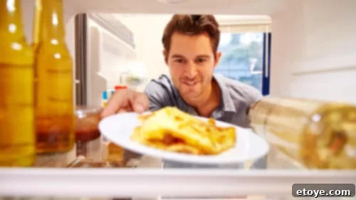 Man pulling out a container of leftovers from the top shelf of a refrigerator