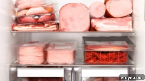 Raw meats including beef, pork, and seafood stored on the bottom shelf of a refrigerator