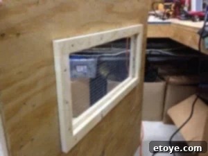 Coop Door Hardware Cloth Detail Close-up of chicken coop door showing hardware cloth secured between siding and trim.