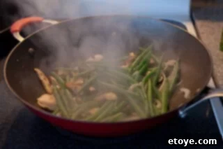 Savory Shiitake and Green Bean Stir-Fry 4 Adding cooked green beans, ginger, and garlic to the wok.