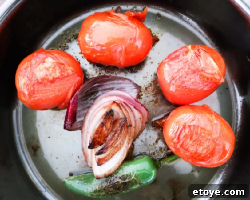 Fire-Kissed Tomato Salsa 3 Overhead shot of charred tomatoes, jalapeños, and onions sizzling in a pan, releasing their smoky aromas.