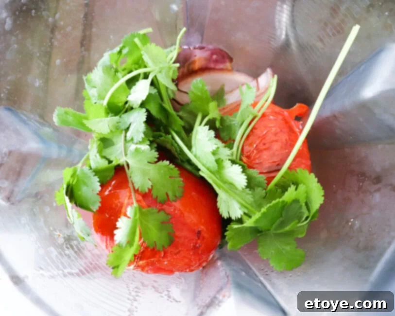 Fire-Kissed Tomato Salsa 4 Charred tomato salsa ingredients in a blender, ready to be pulsed into a delicious sauce.