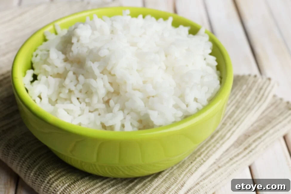 Cooked rice in bowl on wooden background, perfect for fried rice or Buddha bowls