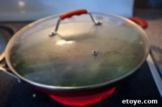 Spicy Miso Steamed Mussels 8 Mussels steaming with vegetables in a wok with a glass lid